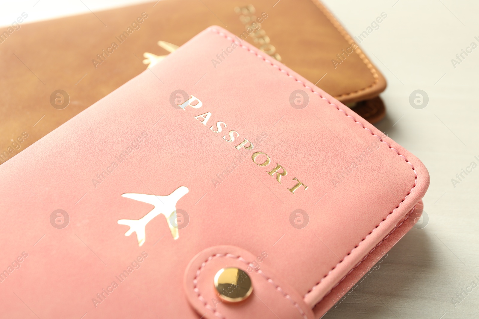 Photo of Two passports in bright covers on white wooden table, closeup