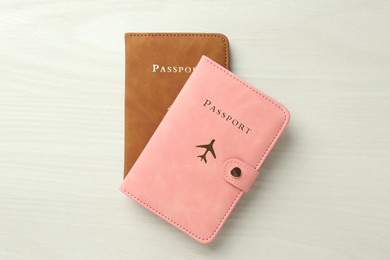 Photo of Two passports in bright covers on white wooden table, top view