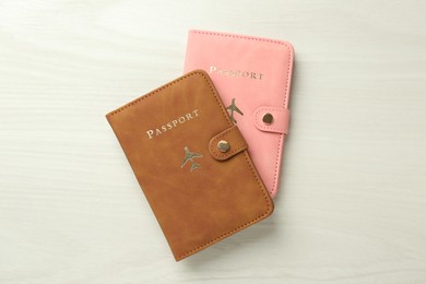 Photo of Two passports in bright covers on white wooden table, top view