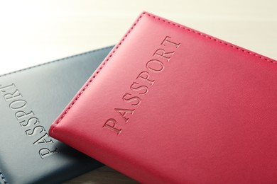 Photo of Two passports in bright covers on white wooden table, closeup