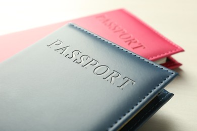 Photo of Two passports in bright covers on white wooden table, closeup