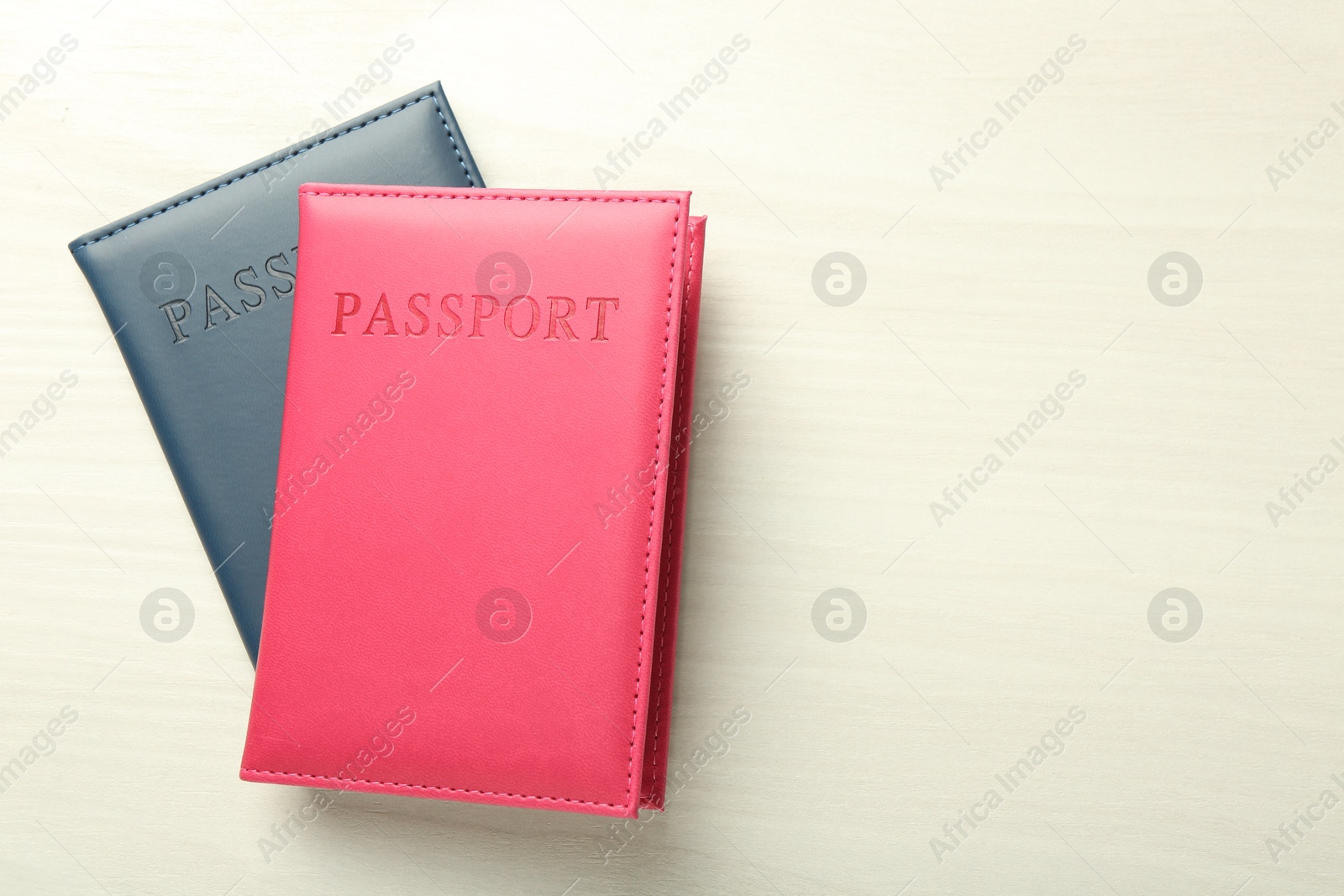 Photo of Two passports in bright covers on white wooden table, top view. Space for text