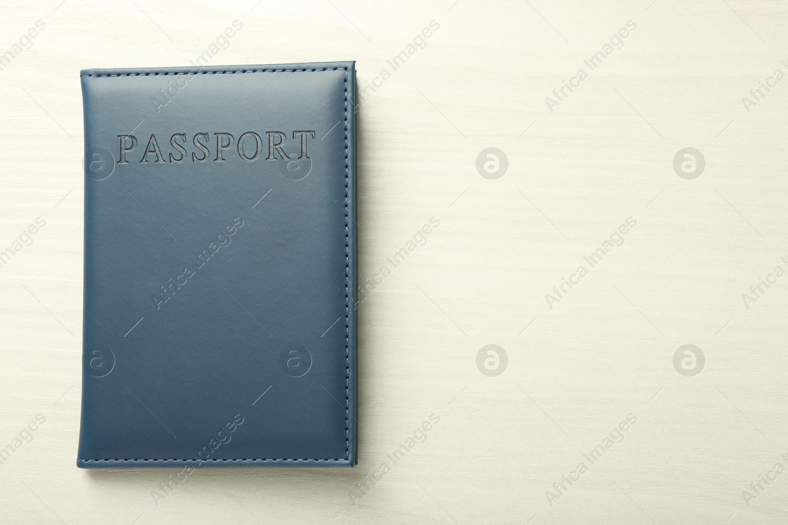 Photo of Passport in grey cover on white wooden table, top view. Space for text