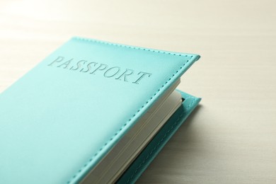 Photo of Passport in bright turquoise cover on white wooden table, closeup