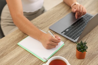 Photo of Student studying at wooden table indoors, closeup