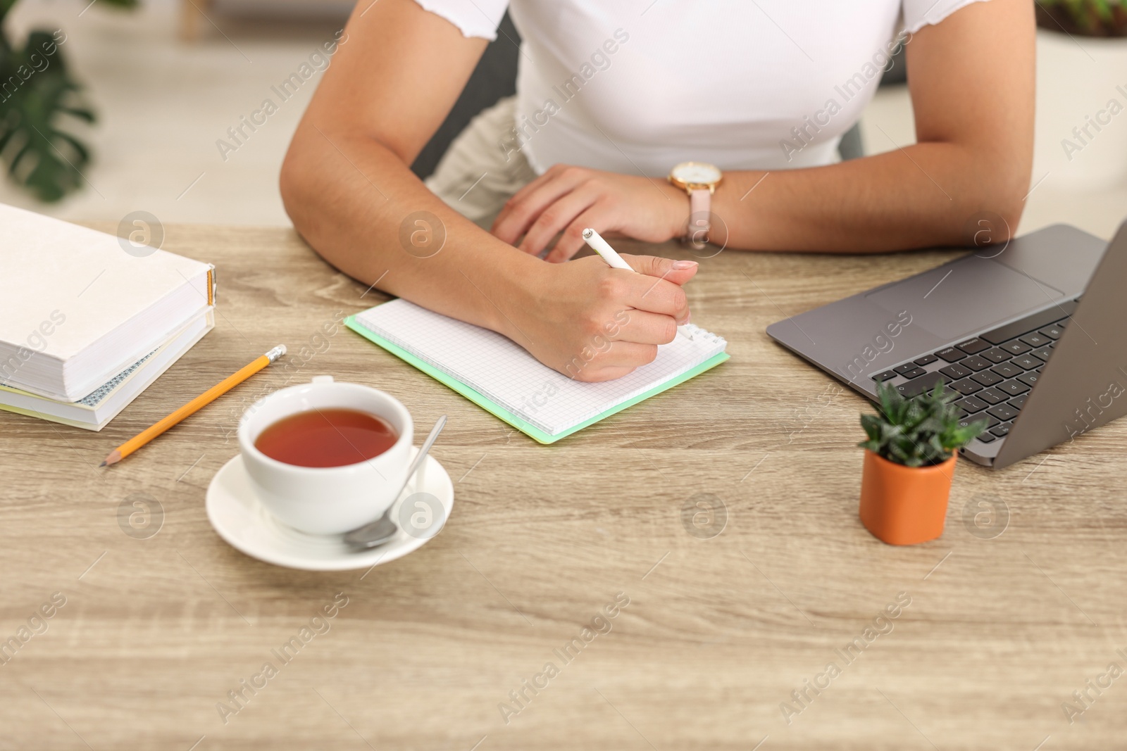 Photo of Student studying at wooden table indoors, closeup