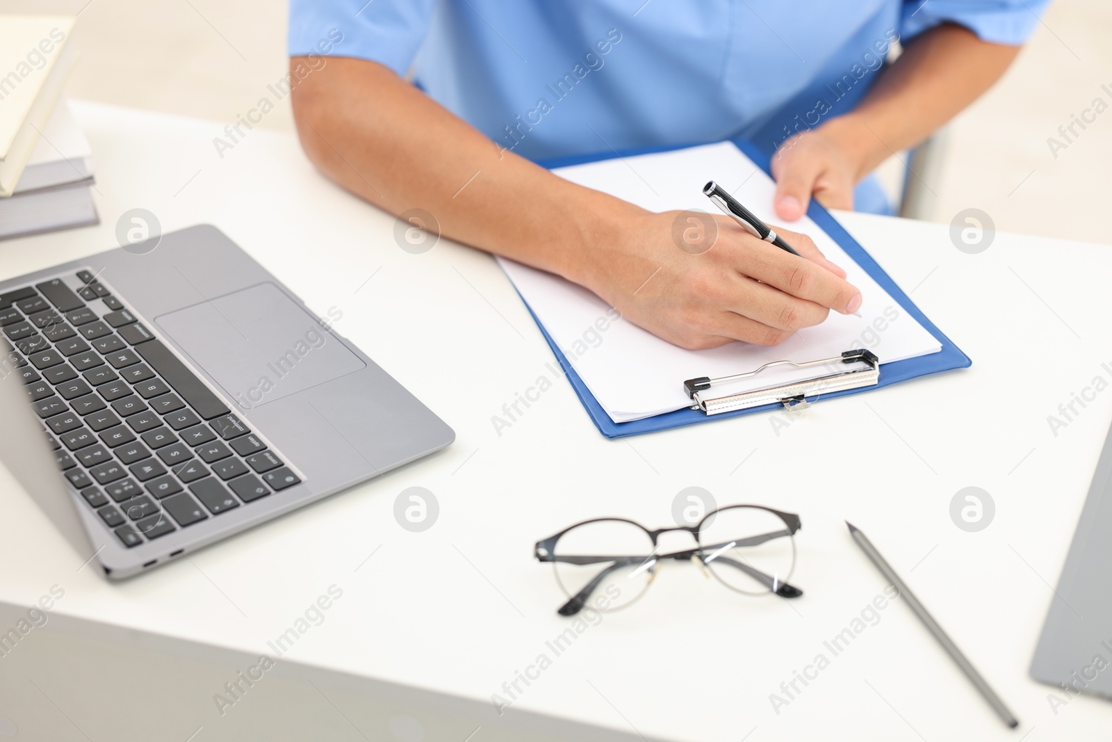 Photo of Medical student taking notes while studying at table indoors, closeup