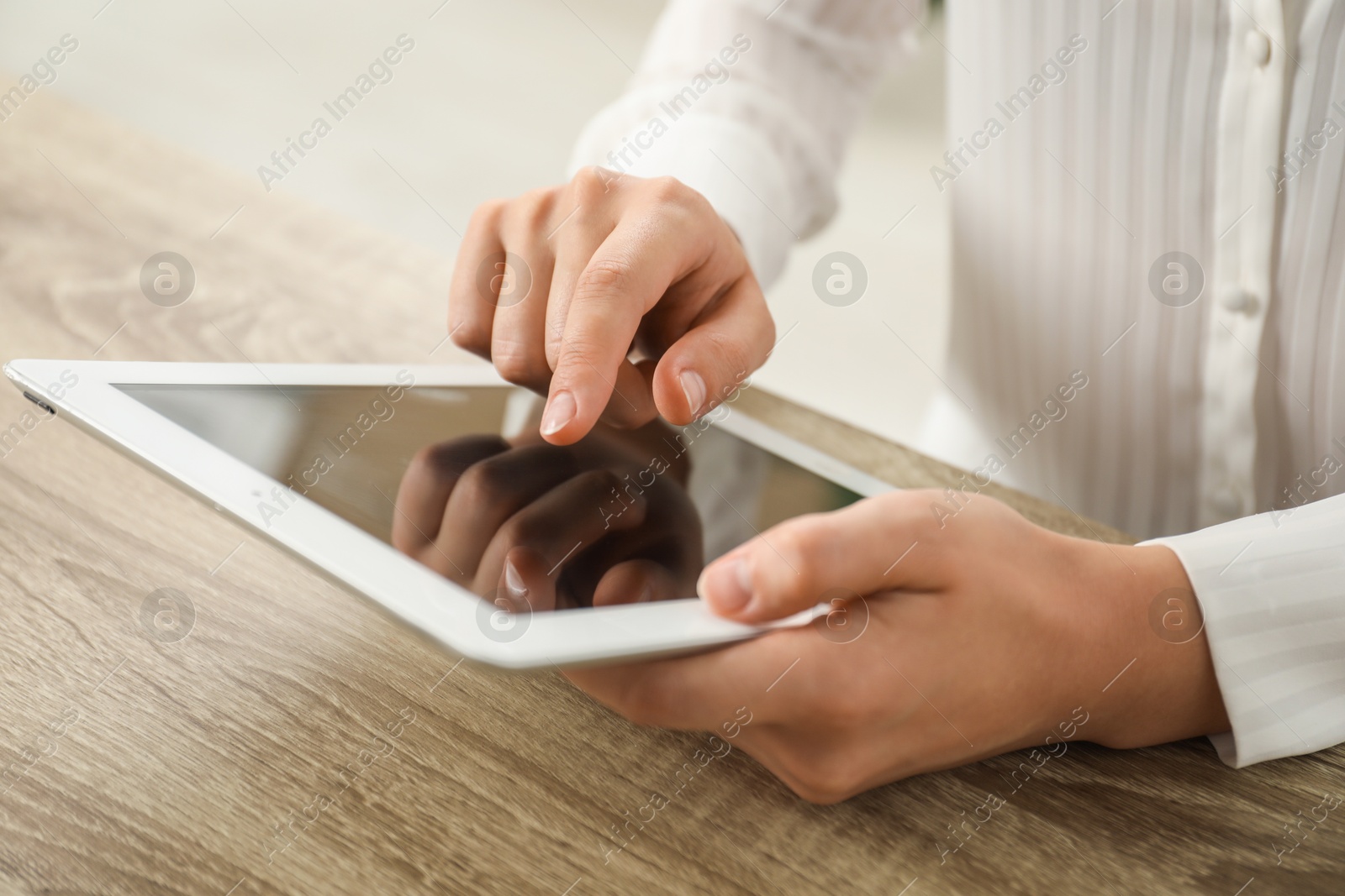 Photo of Businesswoman using tablet at wooden table indoors, closeup. Modern technology