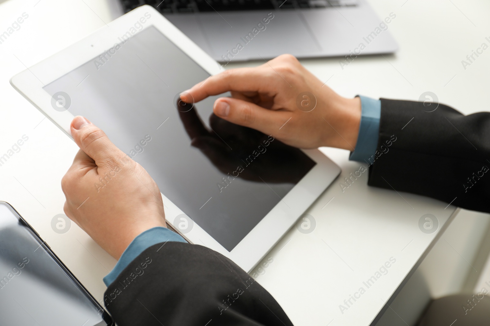 Photo of Businesswoman using tablet at white table indoors, closeup. Modern technology