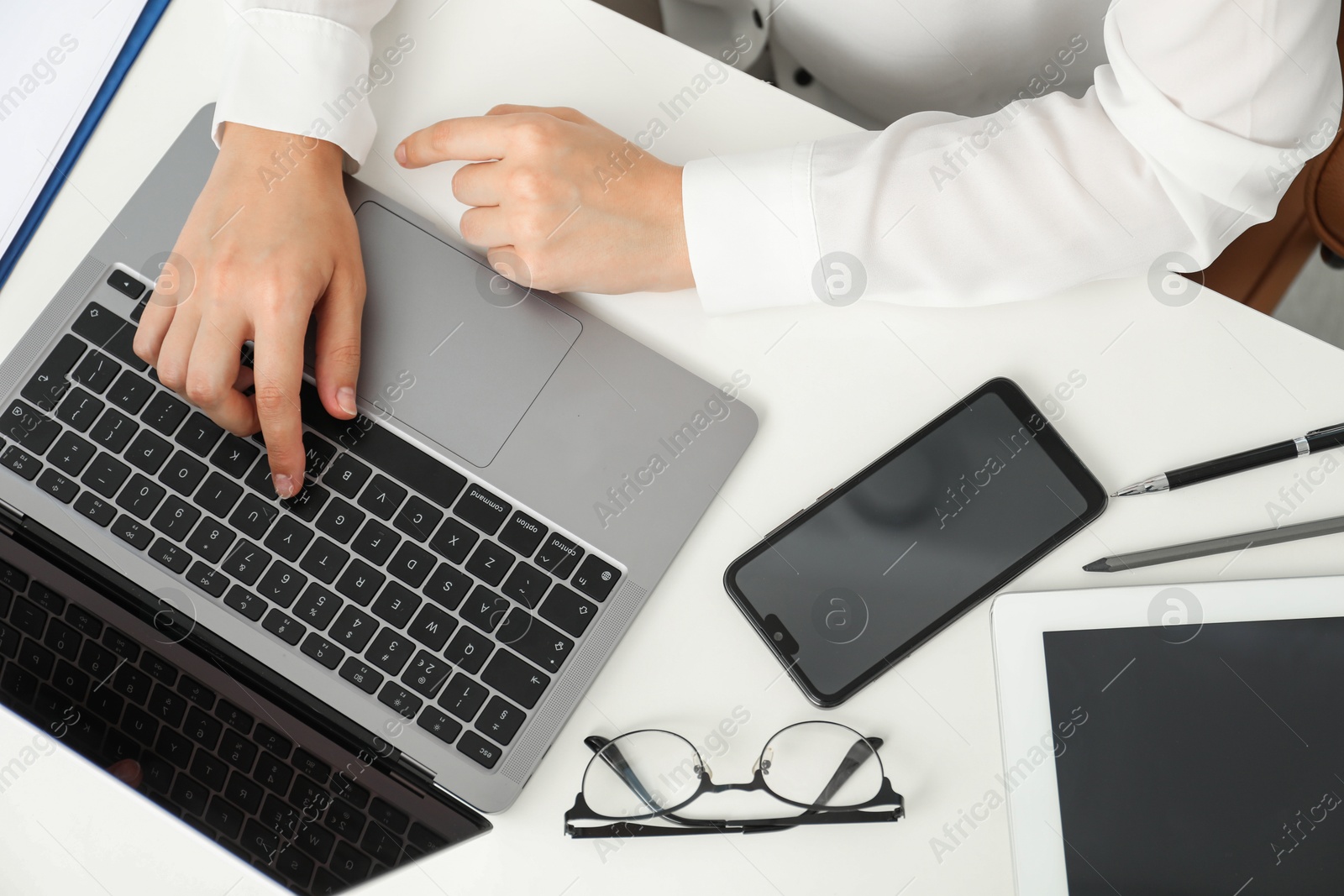 Photo of Businesswoman using laptop at white table indoors, top view. Modern technology