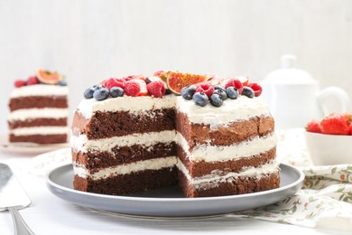 Photo of Delicious chocolate sponge cake with berries served on white wooden table, closeup