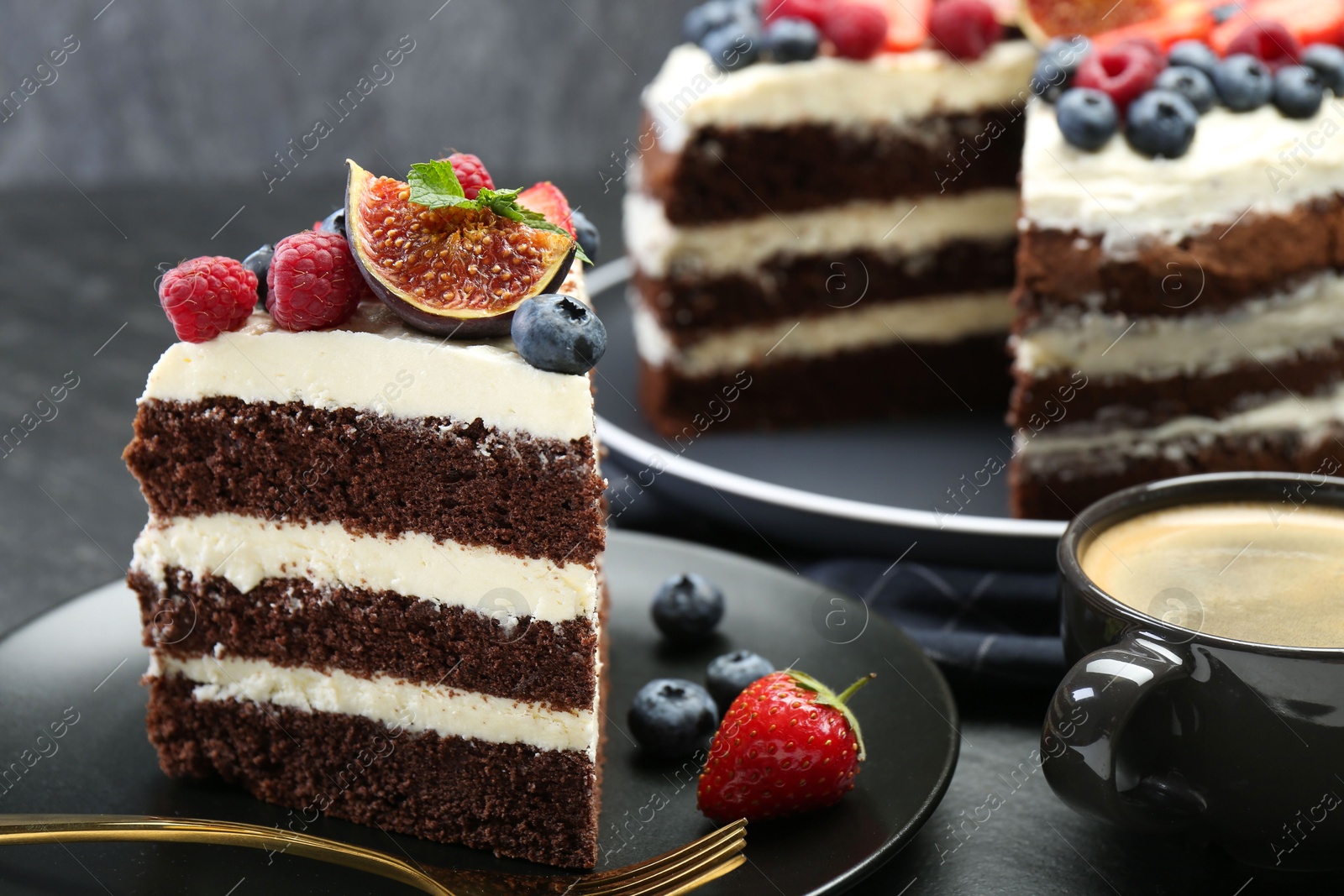 Photo of Piece of delicious chocolate sponge cake with berries and coffee on black table, closeup