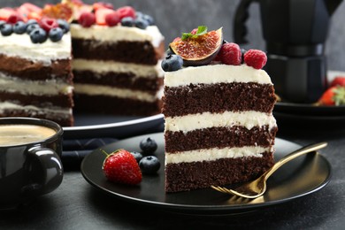 Photo of Piece of delicious chocolate sponge cake with berries and coffee on black table, closeup