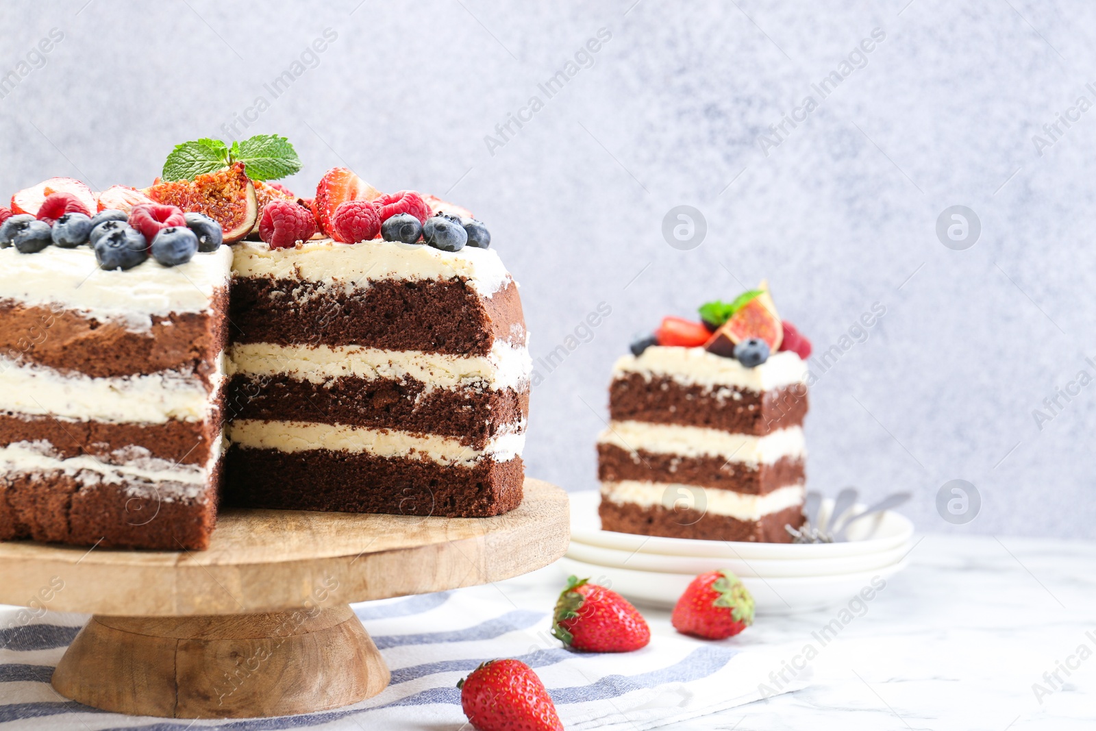 Photo of Delicious chocolate sponge cake with berries served on white table