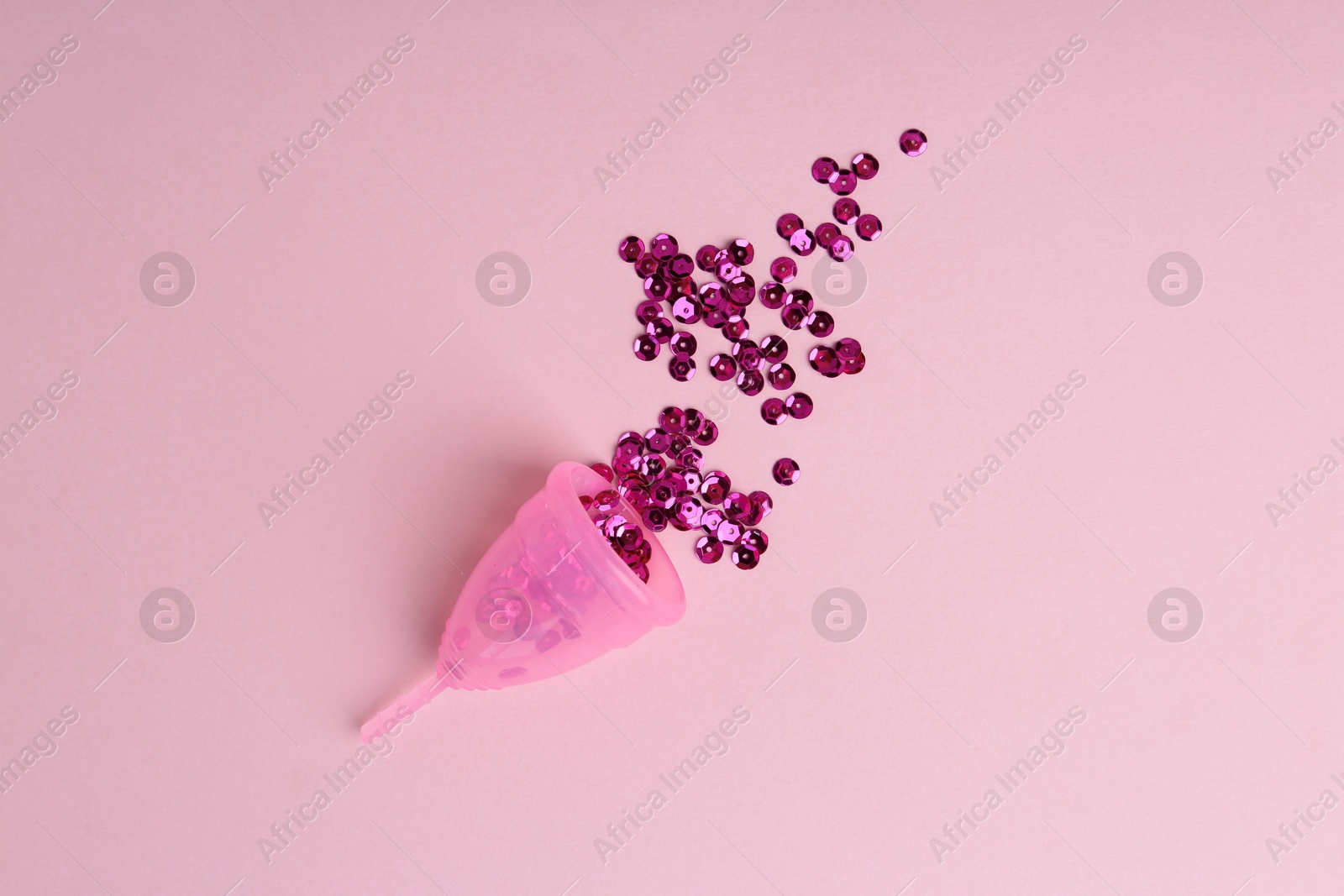 Photo of Menstrual cup with sequins on pink background, top view