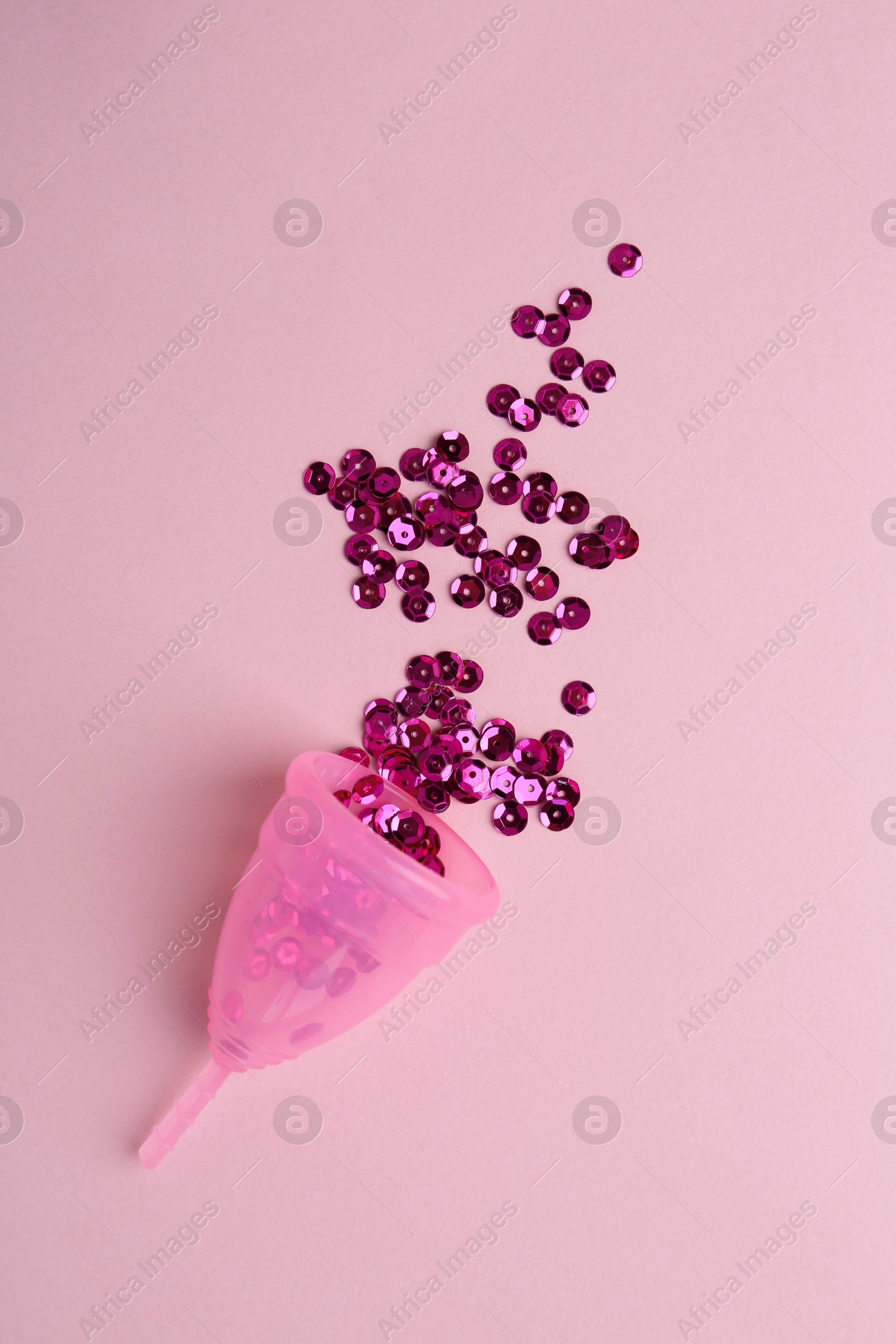 Photo of Menstrual cup with sequins on pink background, top view