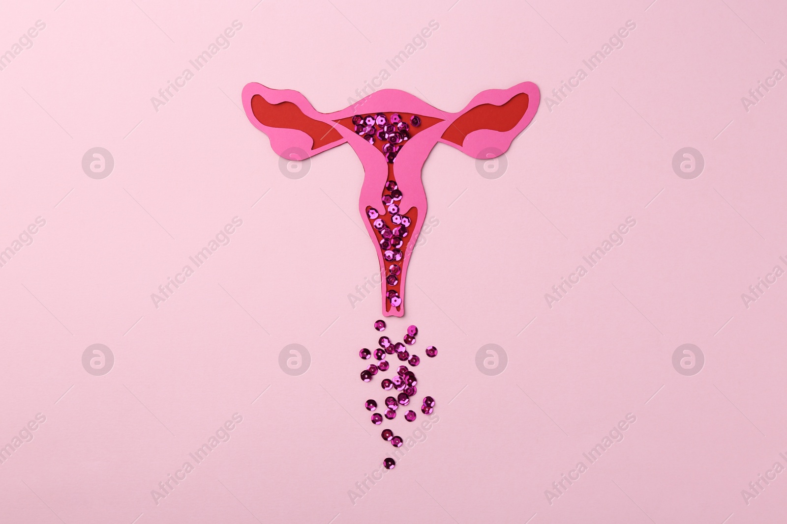 Photo of Menstruation. Paper uterus with sequins on pink background, top view