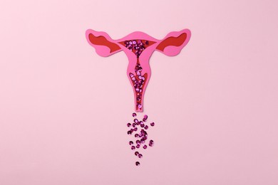 Photo of Menstruation. Paper uterus with sequins on pink background, top view