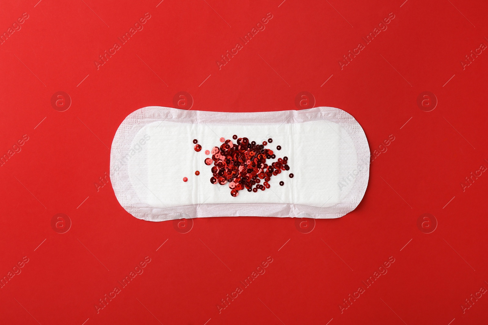 Photo of Menstrual pad with sequins on red background, top view