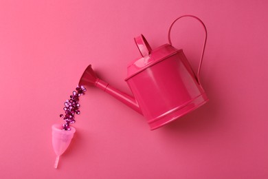 Pouring sequins into menstrual cup from watering can on pink background, top view