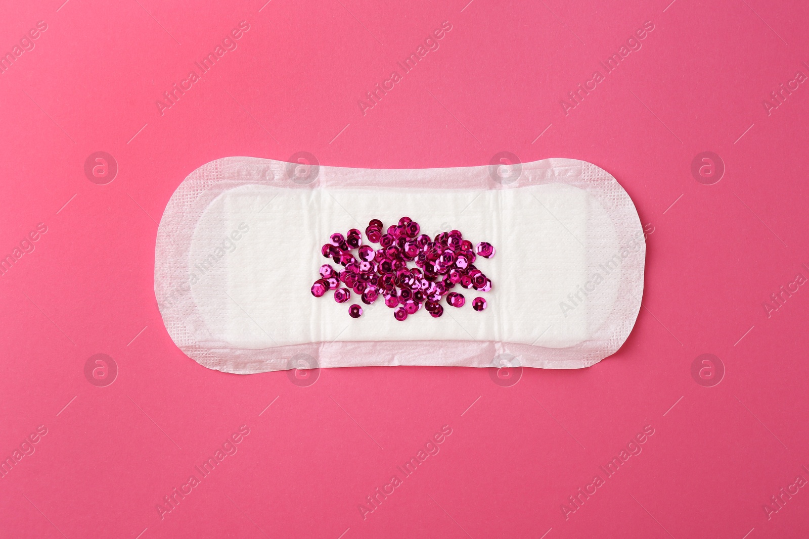 Photo of Menstrual pad with sequins on pink background, top view