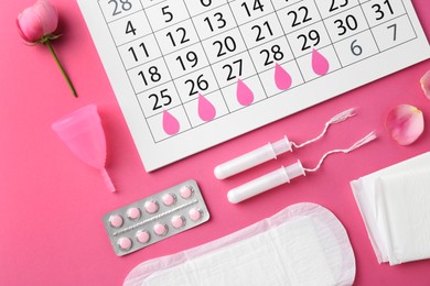 Flat lay composition with calendar and menstrual products on pink background