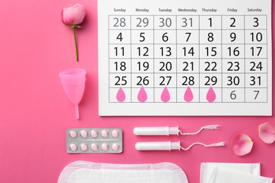 Photo of Flat lay composition with calendar and menstrual products on pink background