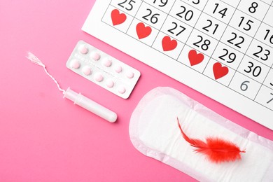 Photo of Flat lay composition with calendar and menstrual products on pink background