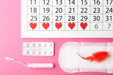 Photo of Flat lay composition with calendar and menstrual products on pink background