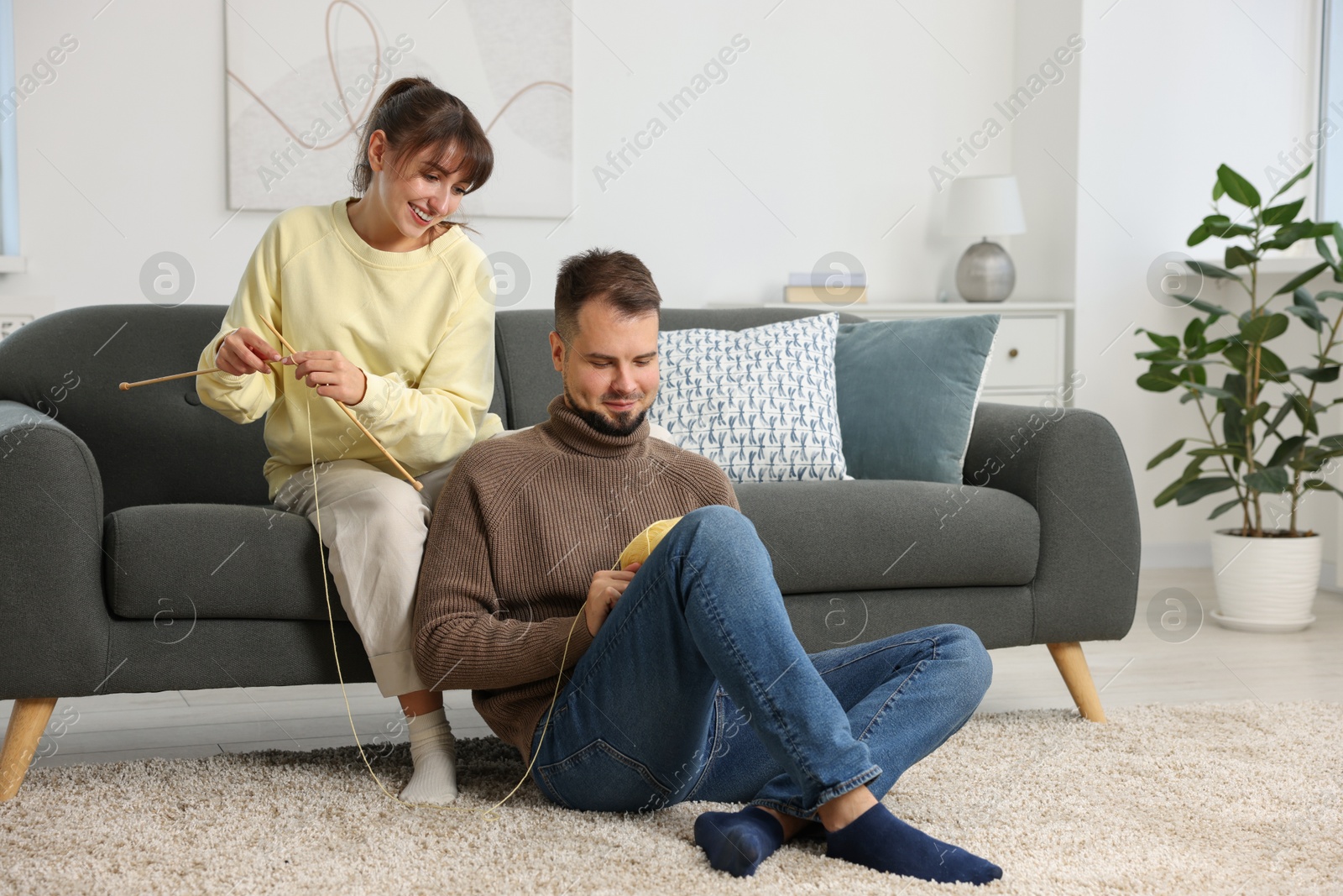 Photo of Woman teaching her boyfriend how to knit at home