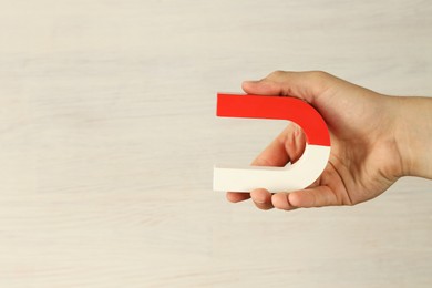 Photo of Man holding horseshoe magnet against white wooden background, closeup. Space for text