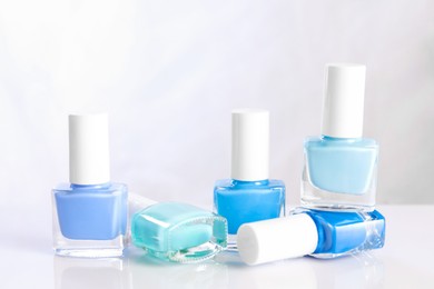 Photo of Set of nail polishes in bottles on mirror table against white background