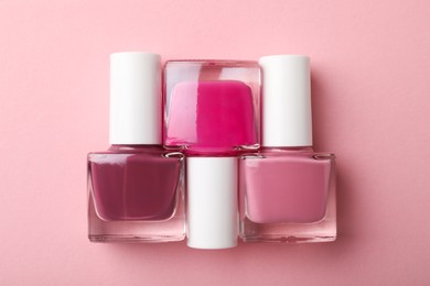 Photo of Set of different nail polishes in bottles on pink background, flat lay