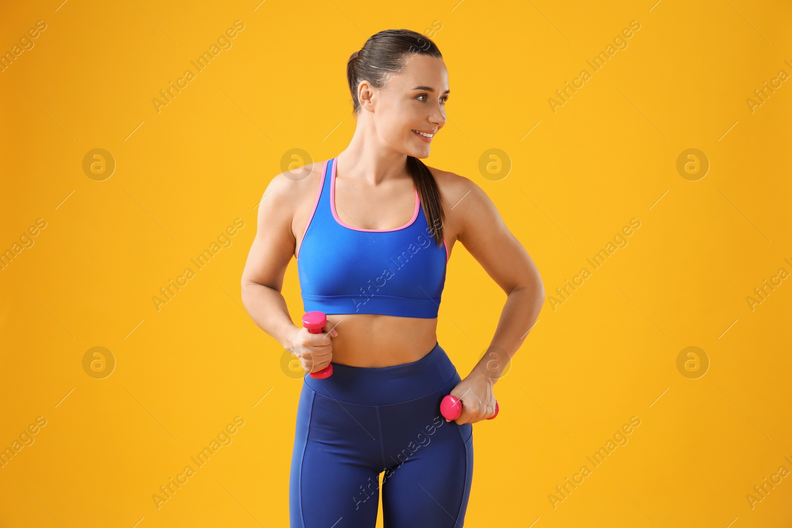 Photo of Woman exercising with dumbbells on orange background