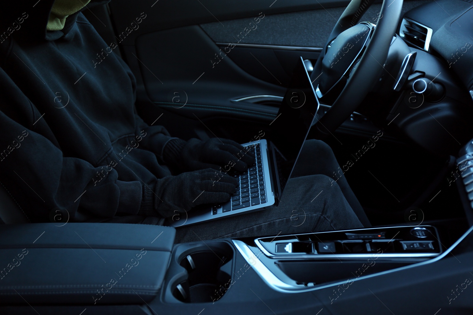 Photo of Thief hacking car system with laptop inside vehicle, closeup