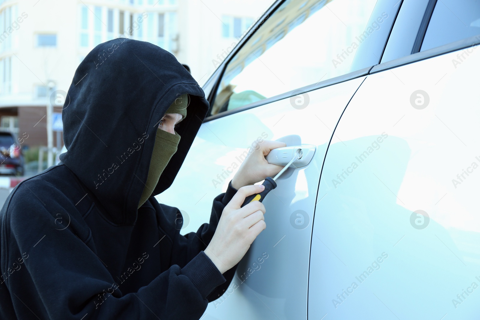 Photo of Thief with screwdriver opening auto door. Car hijacking