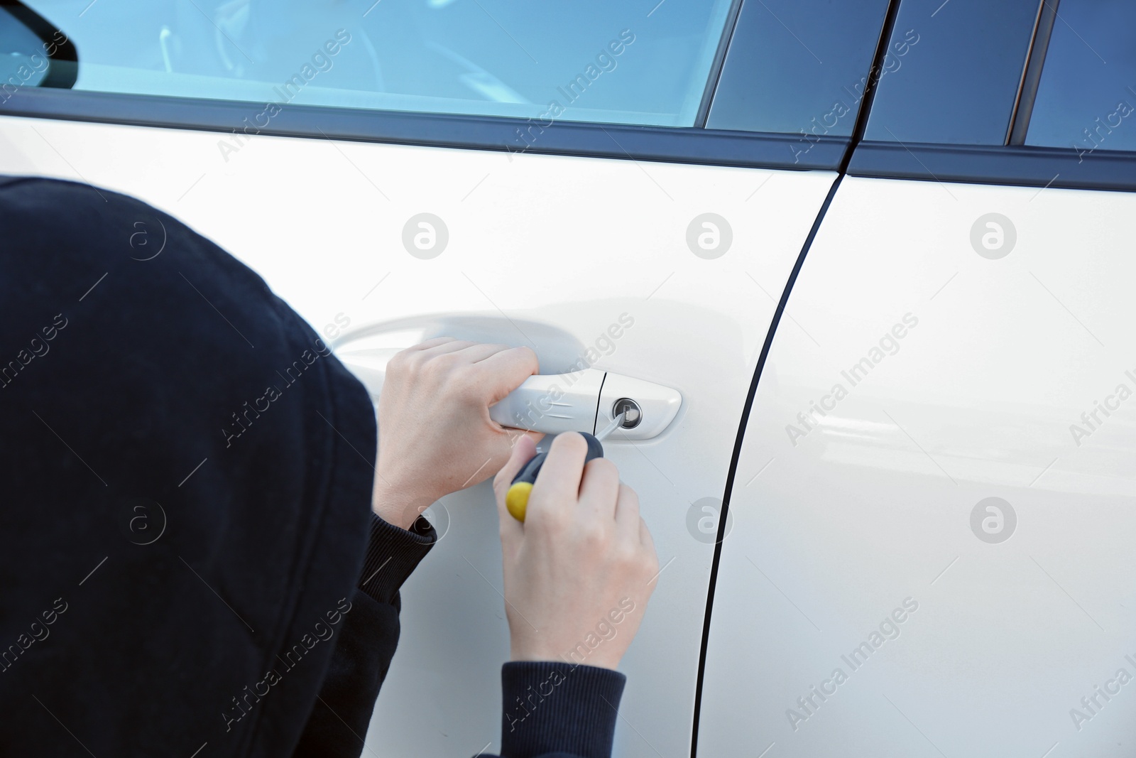 Photo of Thief with screwdriver breaking into car, closeup