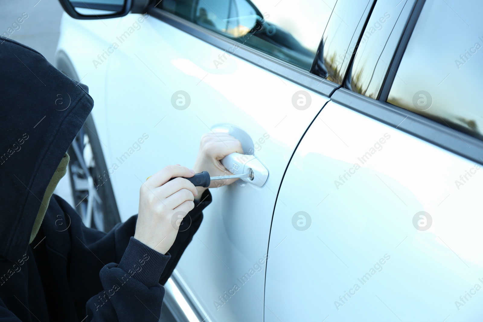 Photo of Thief with screwdriver breaking into car, closeup