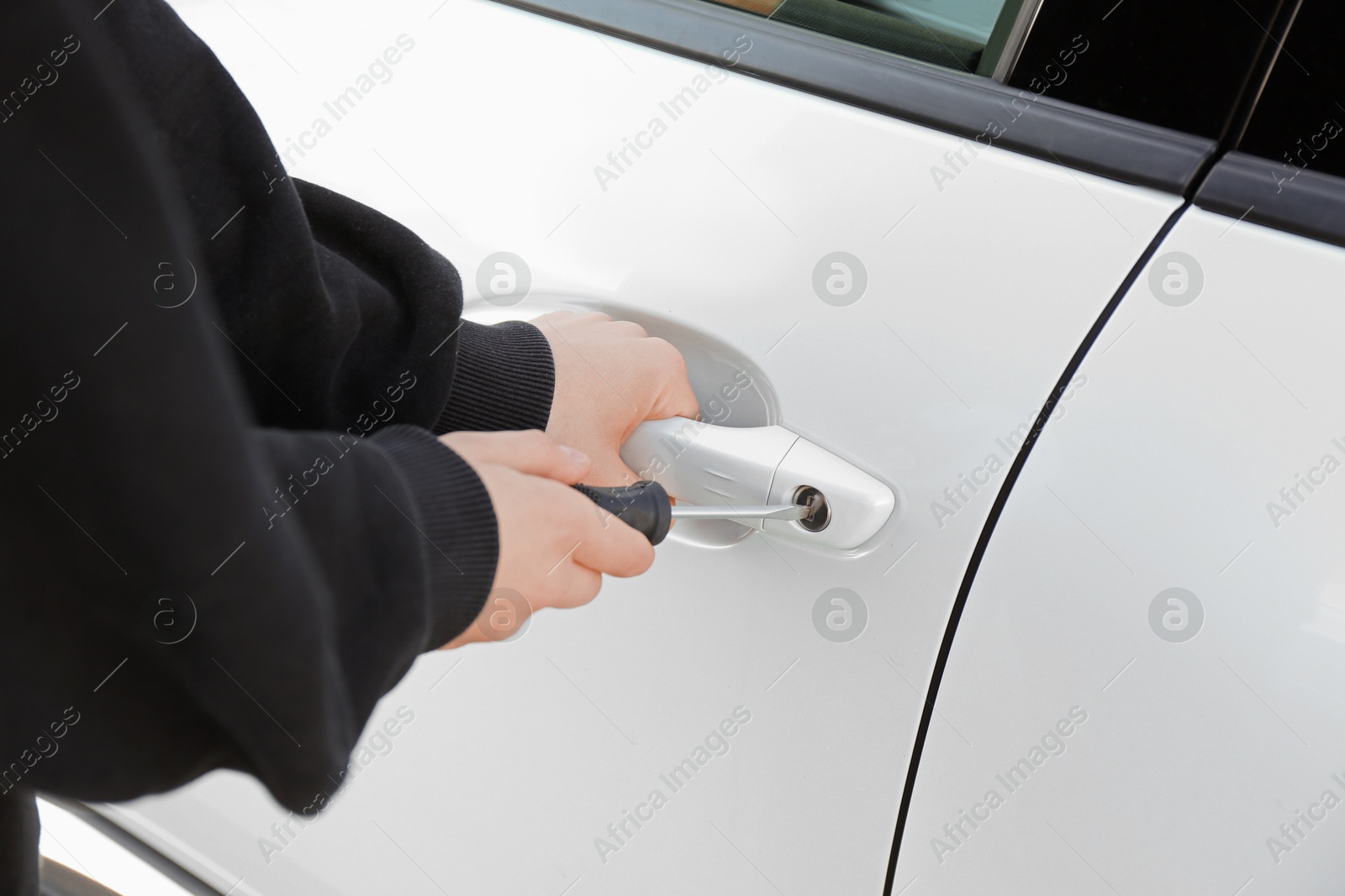 Photo of Thief with screwdriver breaking into car, closeup