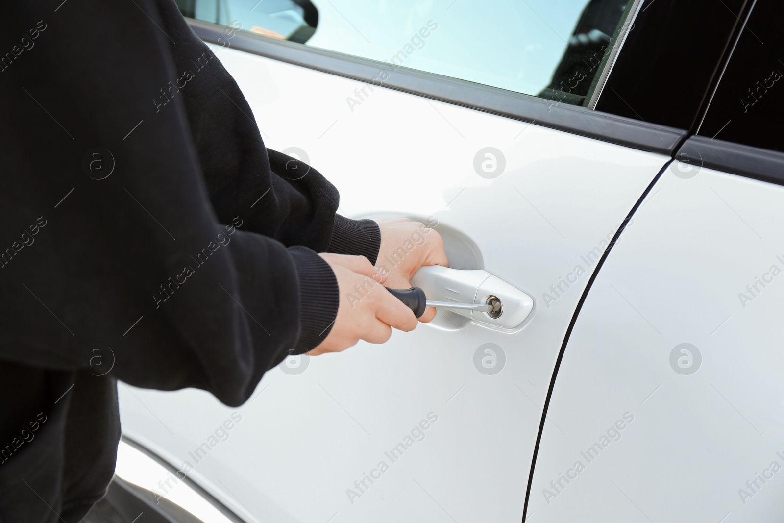 Photo of Thief with screwdriver breaking into car, closeup