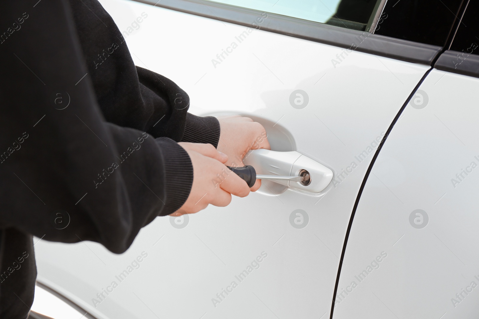 Photo of Thief with screwdriver breaking into car, closeup