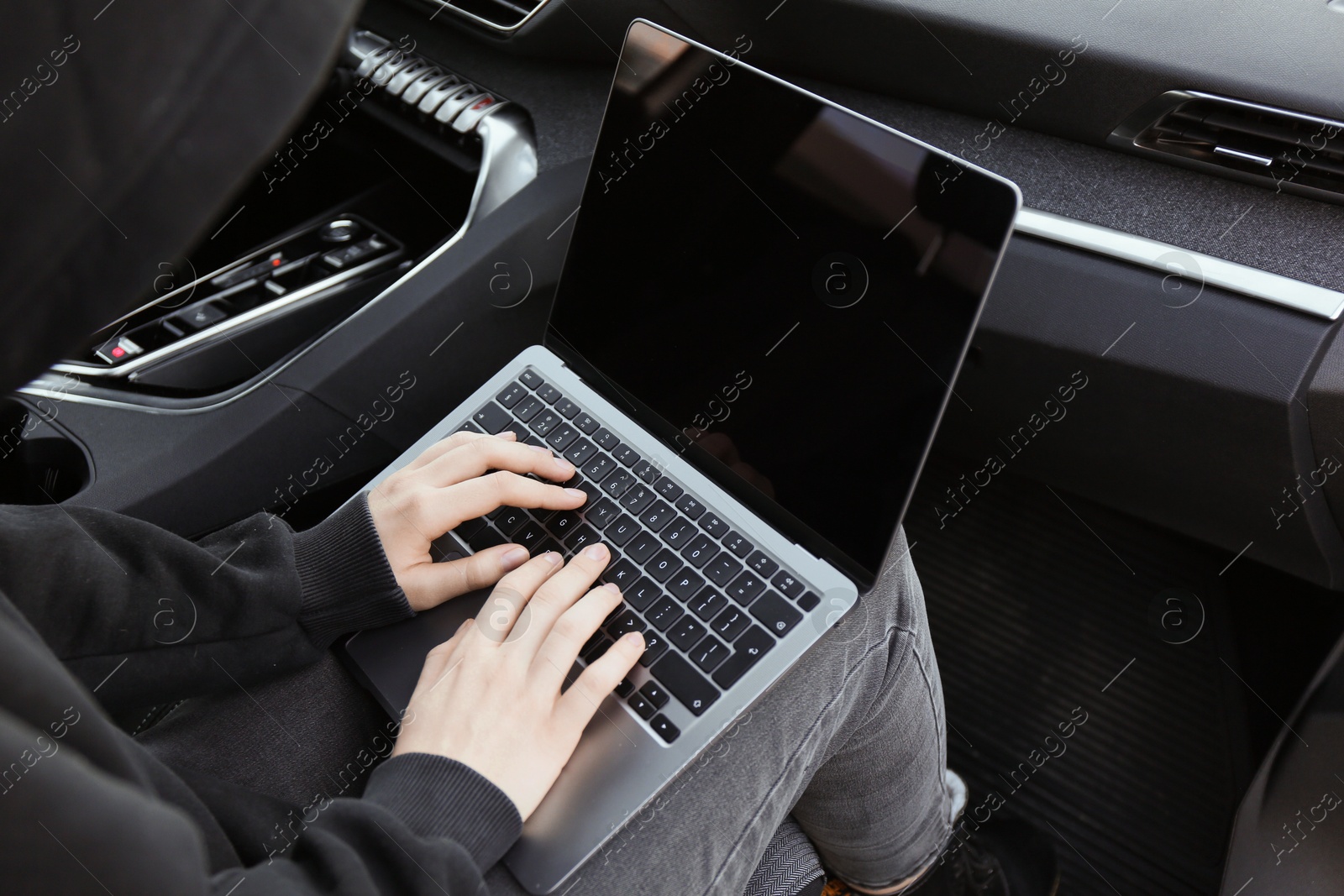 Photo of Thief hacking car system with laptop inside vehicle, closeup