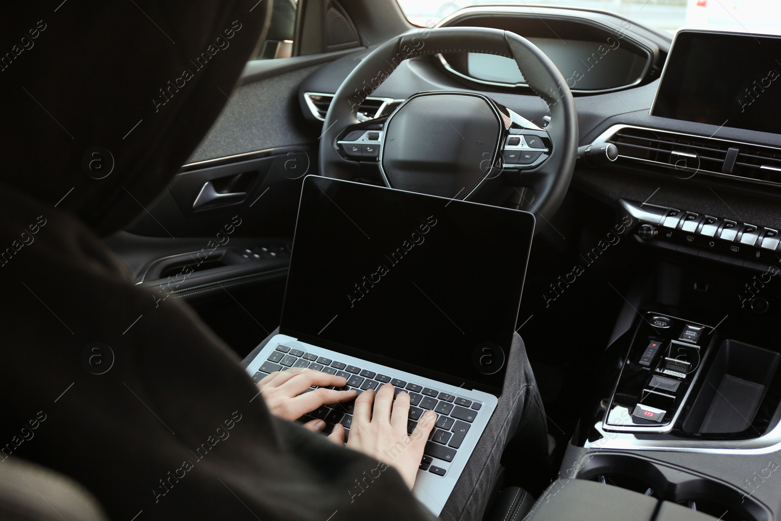 Photo of Thief hacking car system with laptop inside vehicle, closeup