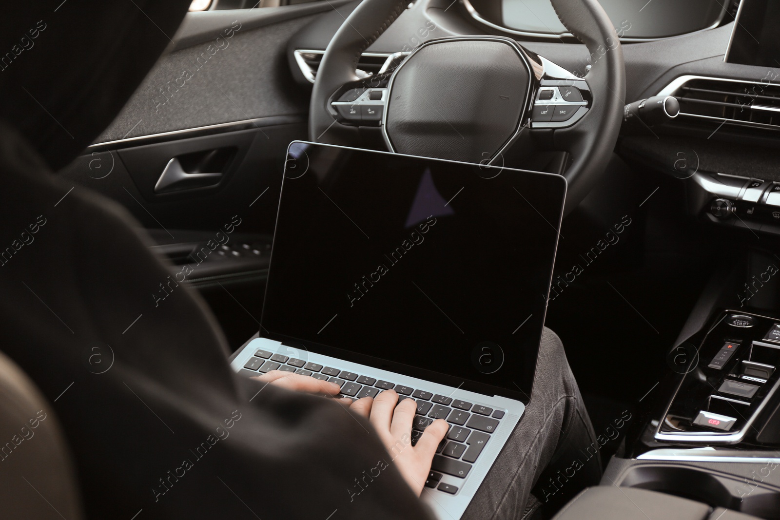 Photo of Thief hacking car system with laptop inside vehicle, closeup