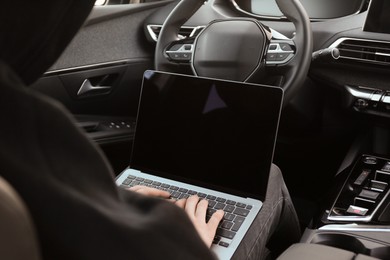 Photo of Thief hacking car system with laptop inside vehicle, closeup