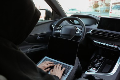 Photo of Thief hacking car system with laptop inside vehicle, closeup