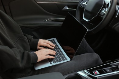 Photo of Thief hacking car system with laptop inside vehicle, closeup