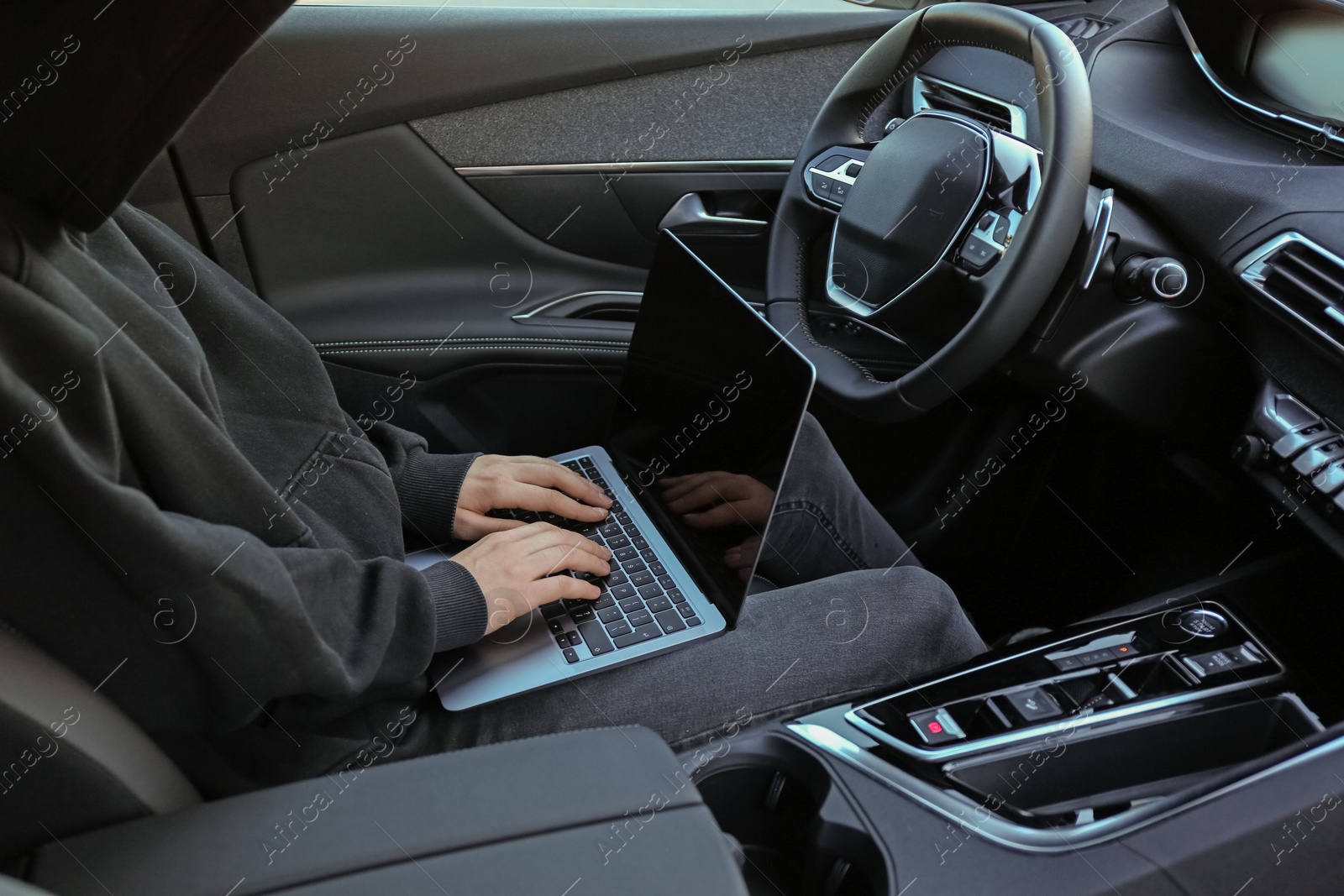 Photo of Thief hacking car system with laptop inside vehicle, closeup