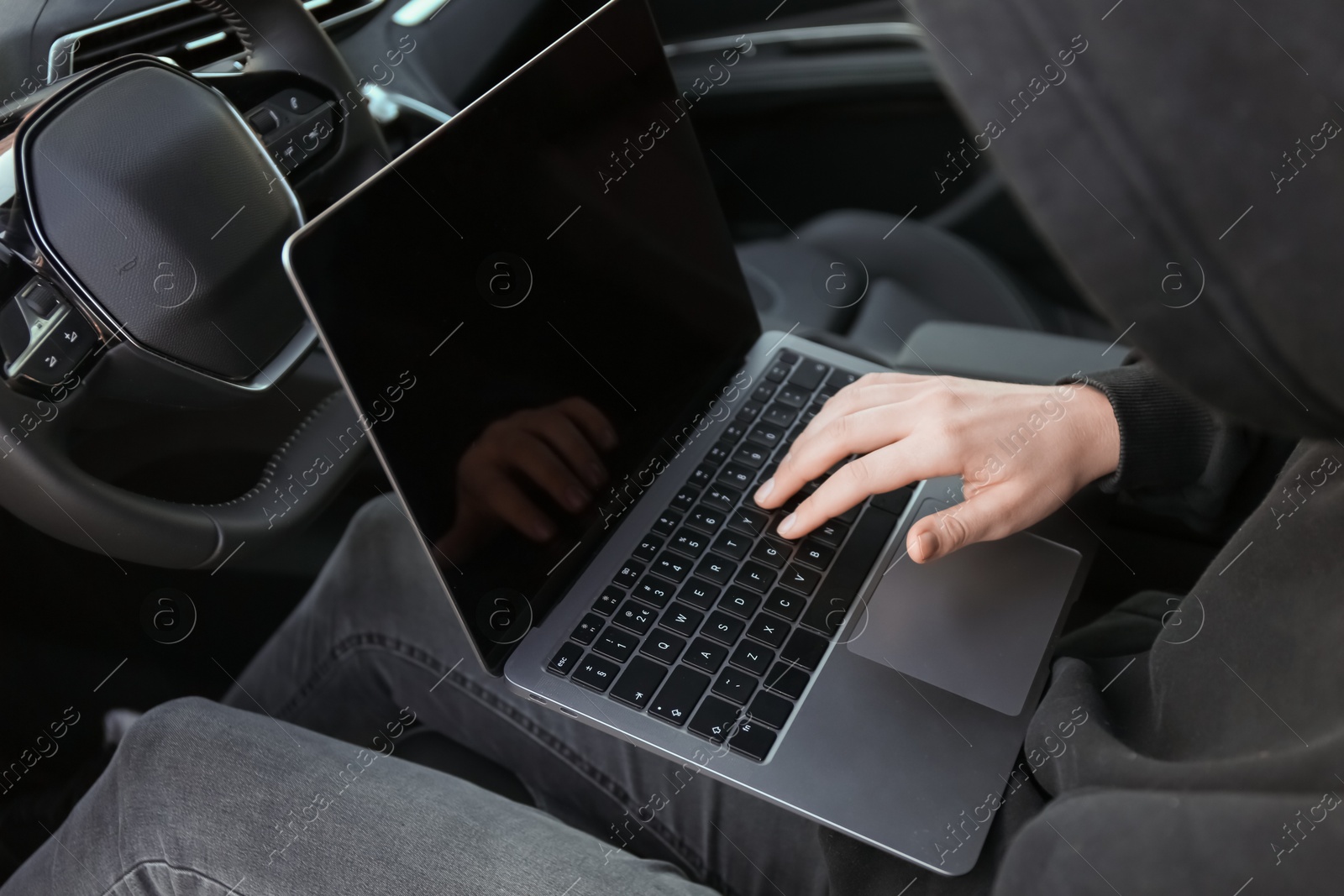 Photo of Thief hacking car system with laptop inside vehicle, closeup