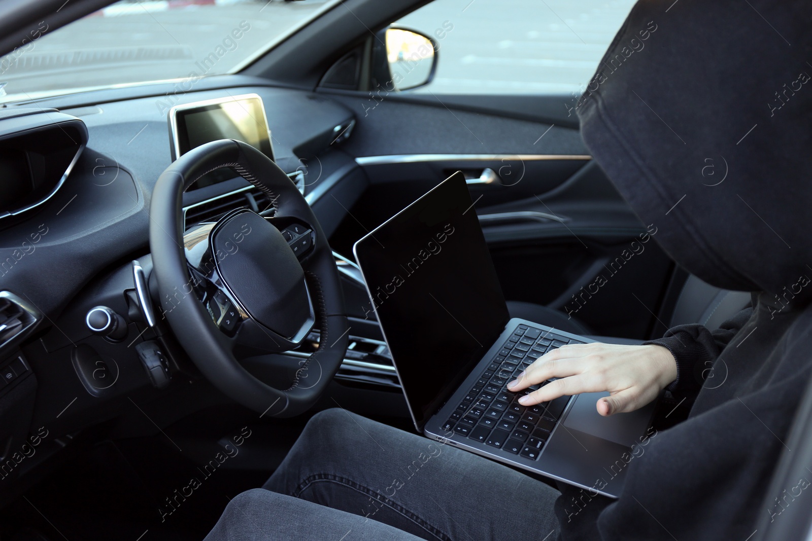 Photo of Thief hacking car system with laptop inside vehicle, closeup